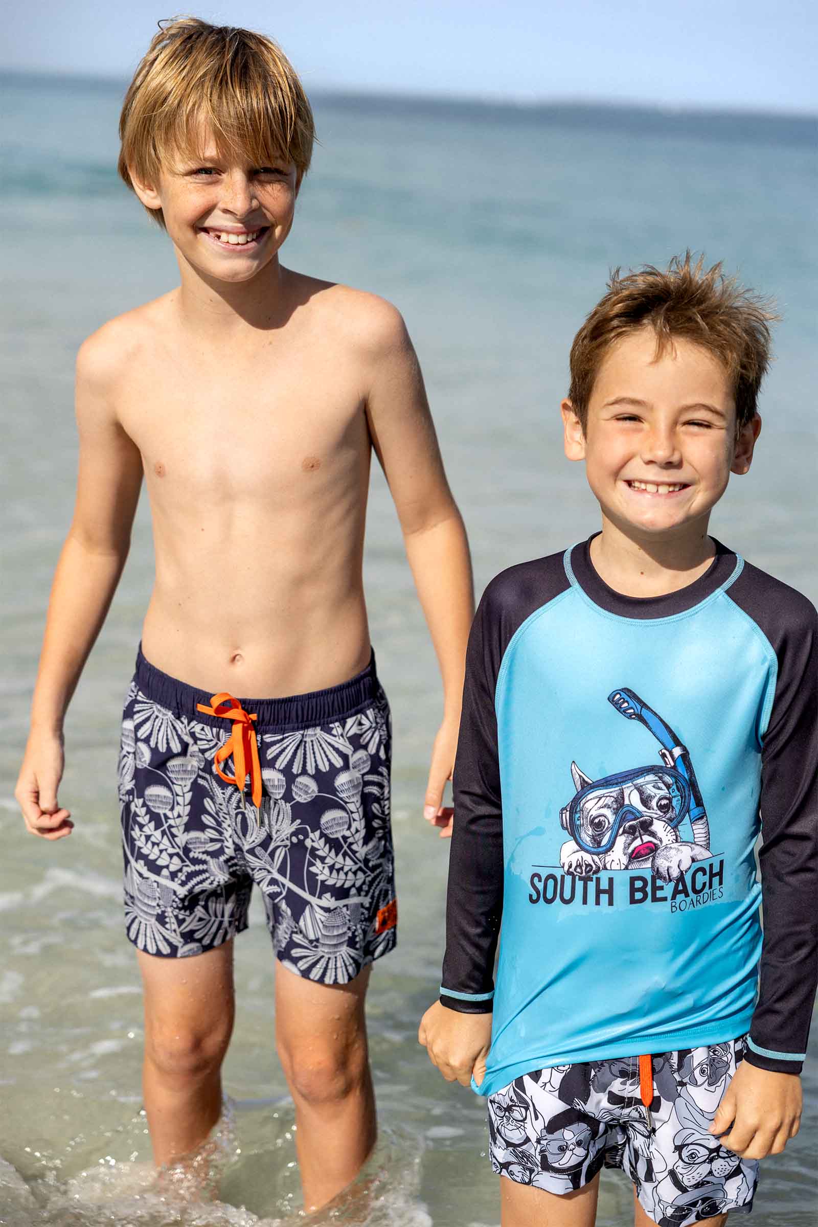 Boys wearing South Beach Boardies long sleeve rashie UPF50 made from recycled plastic bottles, and Dogs are the Best People and Bush Banksia boardies made from recycled plastic bottles.