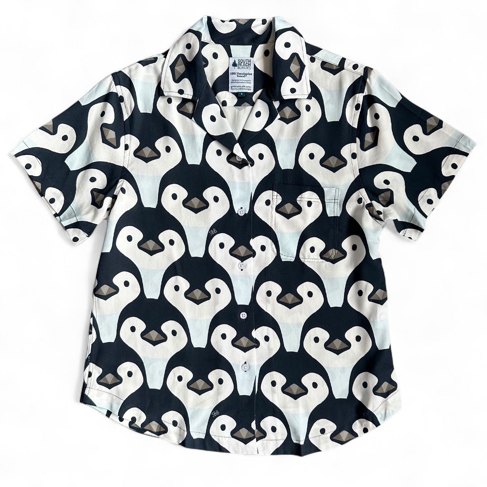 Short-sleeve women's cuban collar shirt with penguin pattern on a white background, made by South Beach Boardies