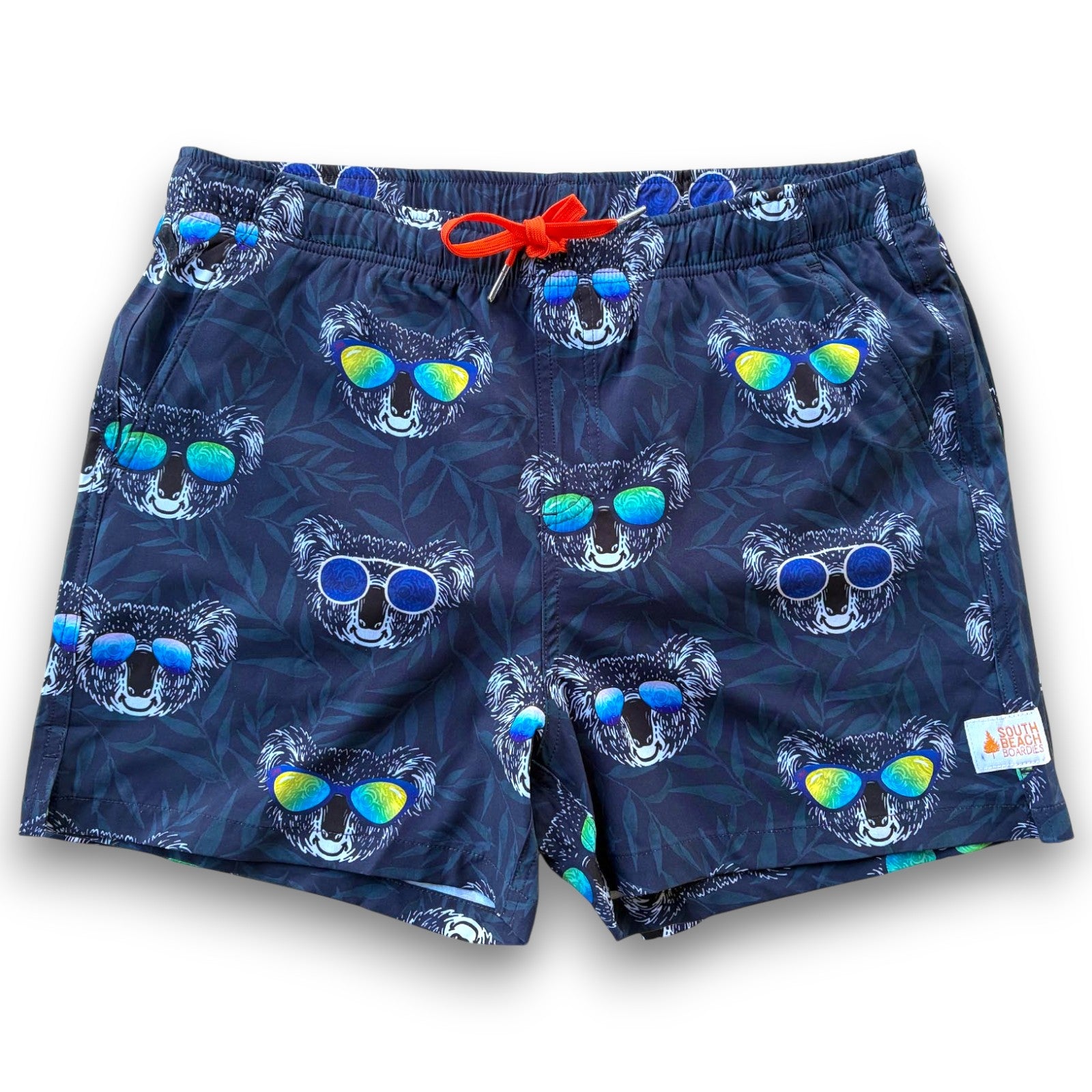Navy swim shorts with koala pattern wearing sunglasses on a blue leafy background - South Beach Boardies made from recycled plastic bottles Kid Koala Men's Stretchy shorts