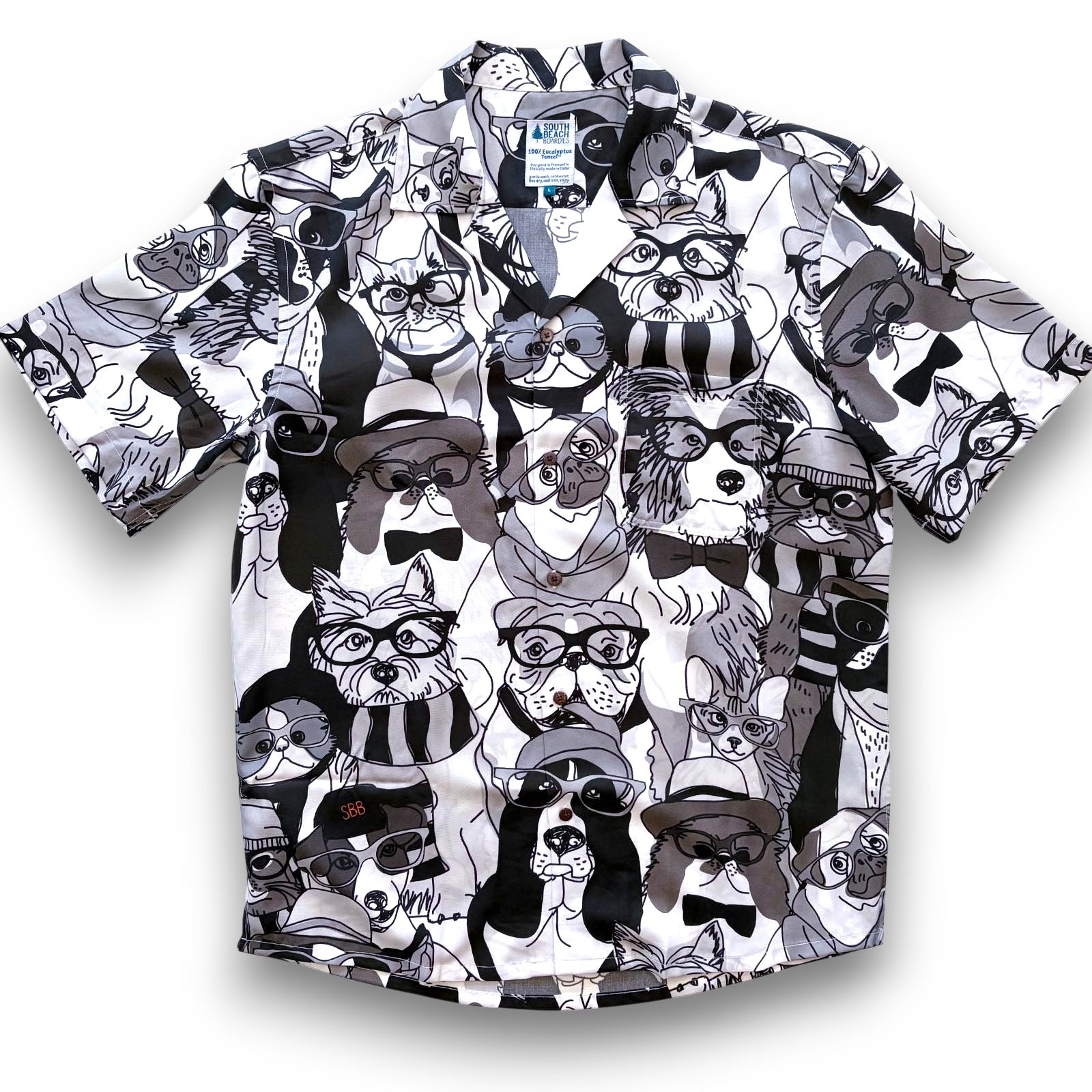 Cuban collar mens shirtswith a black and white pattern of stylized dogs and cats wearing hats and sunglasses on a white background, by South Beach Boardies, front view