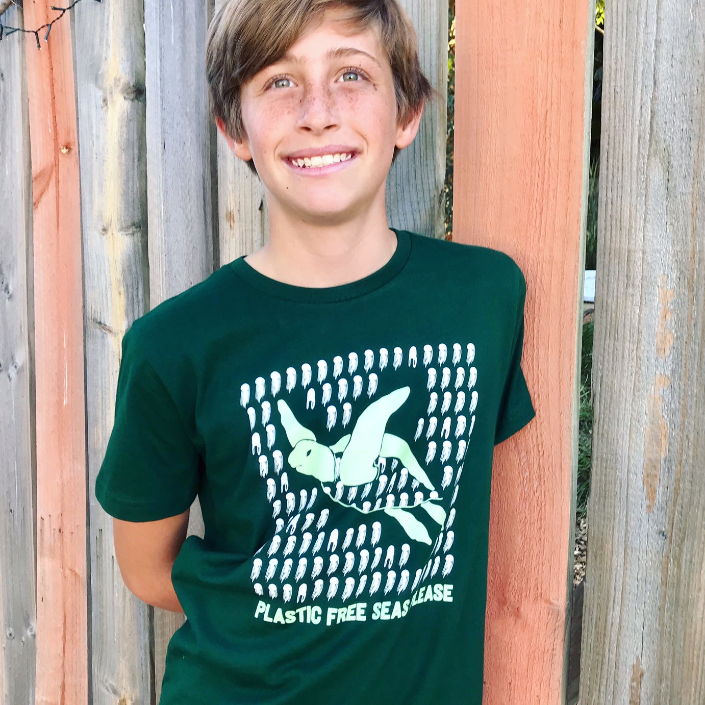Plastic Free Seas Please graphic bottle green turtle tshirt being worn by boy