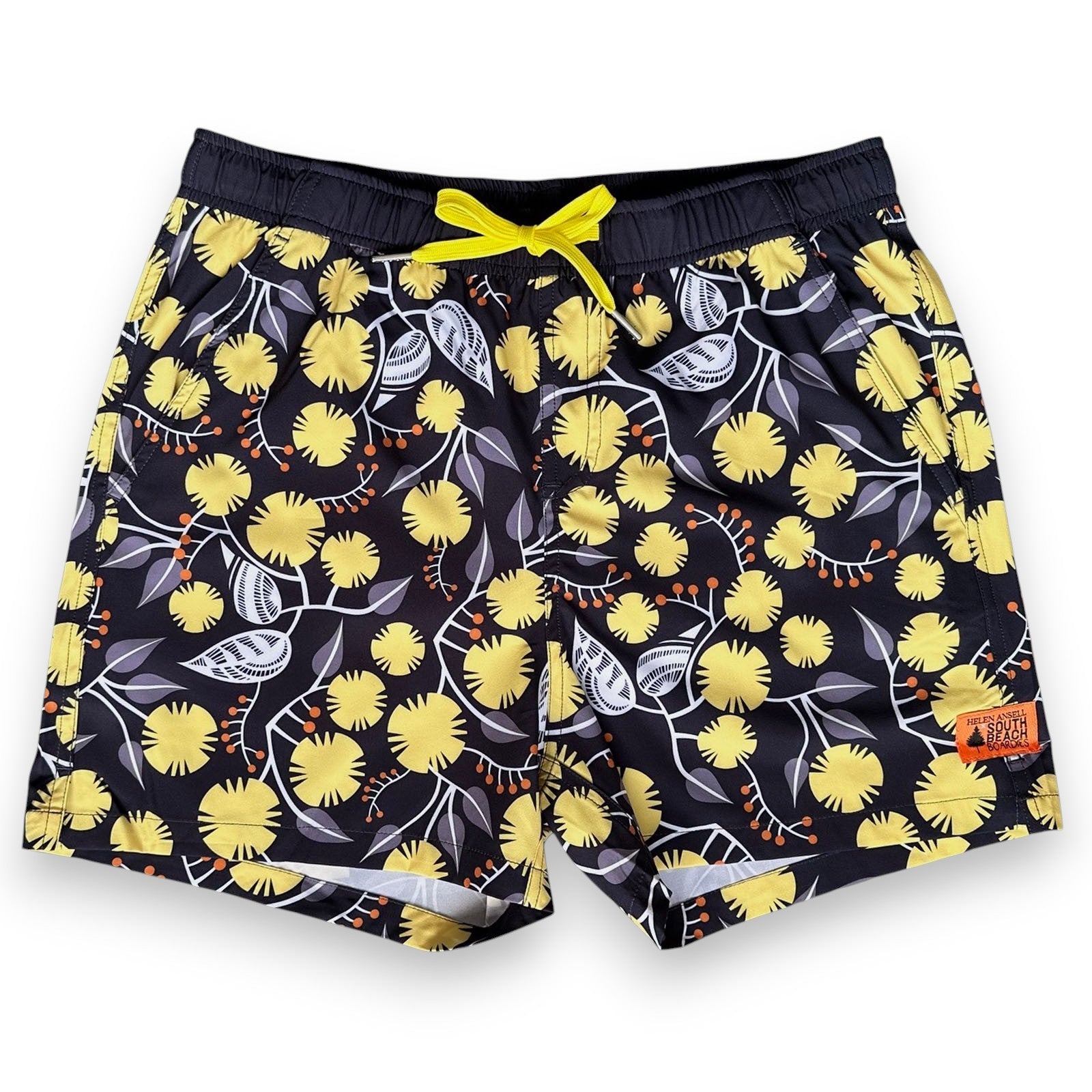 West Australian wattle patterned shorts with yellow flowers and grey leaves on a dark background, by South Beach Boardies x Helen Ansell, front view
