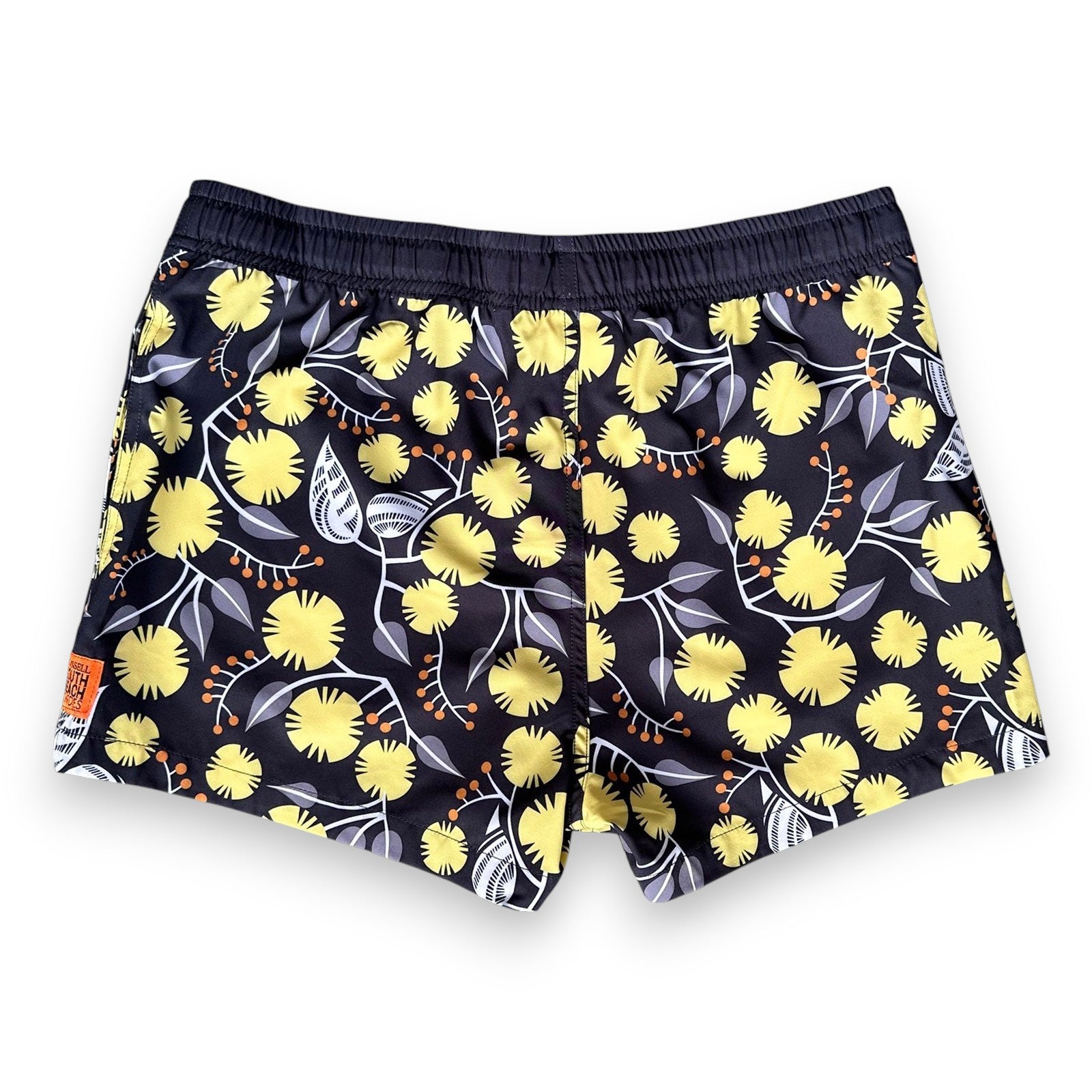 West Australian wattle patterned women's swim shorts with yellow flowers and grey leaves on a dark background, by South Beach Boardies x Helen Ansell, back view