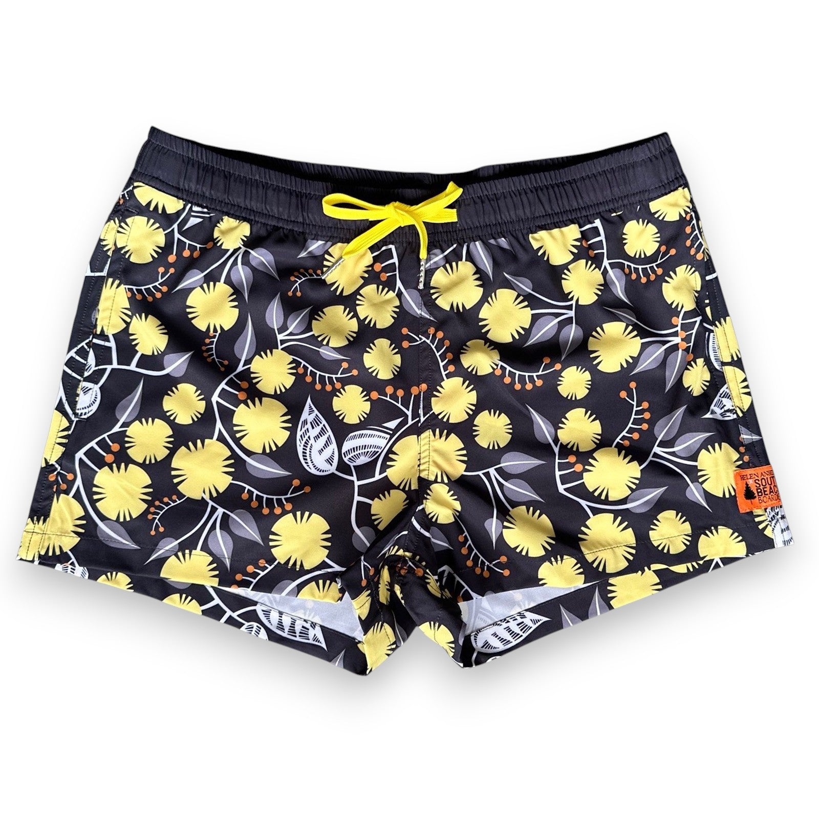 West Australian wattle patterned women's swim shorts with yellow flowers and grey leaves on a dark background, by South Beach Boardies x Helen Ansell, front view