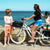 Boy wearing SBB Kids Going Out Boardies in Orange Crush talks to Woman on Bike wearing Cute Butt Boardies in Sea Stripe