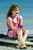 Girl wearing SBB Kids Kids Long Boardies recycled Coral Stripe board shorts, sitting on paddle board