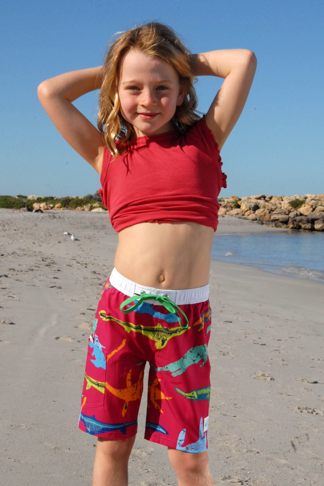 Girl wearing South Beach Boadies from recycled plastic. Kids Long Boardies in Plesiosaurs, front view